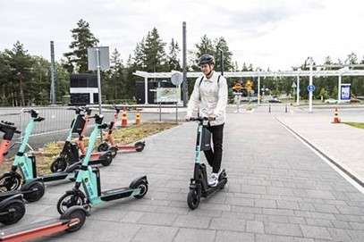 Sähköpotkulautoja ja ihminen ajamassa sähköpotkulaudalla Kaupissa.