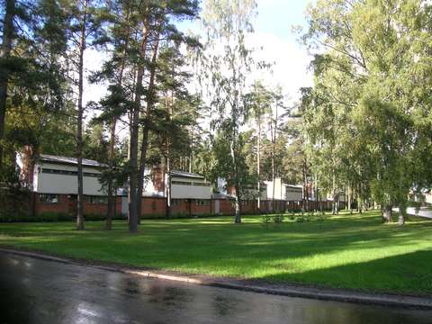 The 1–2-storey Ketjutalot buildings border a wide grassy area on the edge of Menninkäisentie.