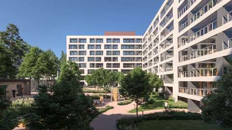 View of the sheltered green courtyard of the new blocks of flats. The buildings have light-coloured facades and glazed balconies.