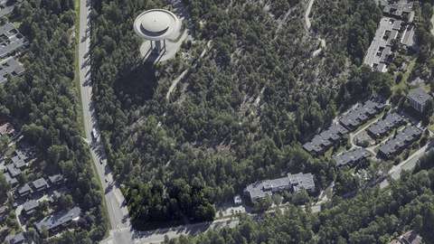 Planeringsområdet är en tomt med träd i förgrunden av bilden, i hörnet av Gäddviksgatan och Gäddbergsvägen.