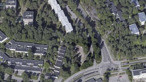 Planeringsområdet är delvis en tomt med träd i förgrunden av bilden, i hörnet av Gäddviksgatan och Gäddbergsvägen.