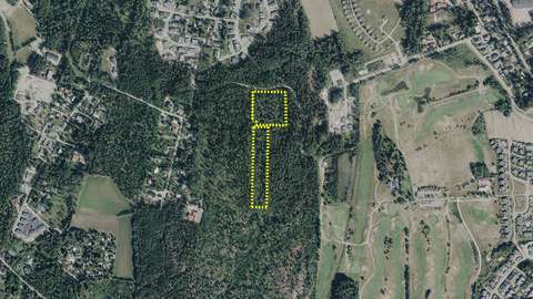 Skogigt område, som är delvis omgivet av fält, på vilket man har ritat en områdesavgränsning.