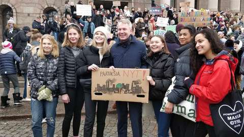 Opiskelijat poseeraavat eduskuntatalon edessä Pekka Haaviston ympärillä.