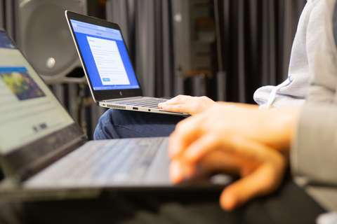 Henkilö käyttää läppäriä istuen