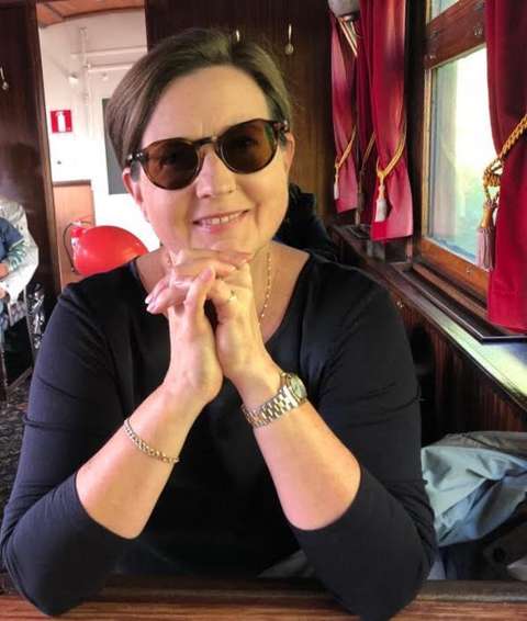 Anne katsoo aurinkolasit päässä hymyillen kameraan. 