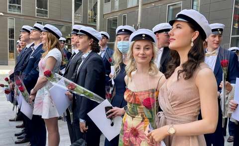 Ylioppilaat seisovat ulkona lakit päässä. 