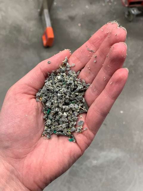 Muovijätteestä hienonnettua harmaata muovisilppua kämmenellä.