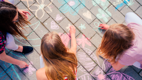 Lapset piirtävät asfalttiin väriliiduilla kukkakuvioita.