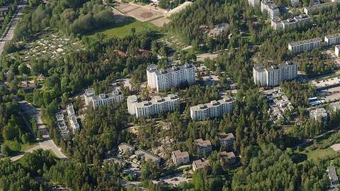 Ett somrigt flygfoto av kvarteret där objektet för ändringen ligger. Flervåningshus på en kulle och skogiga slänter.