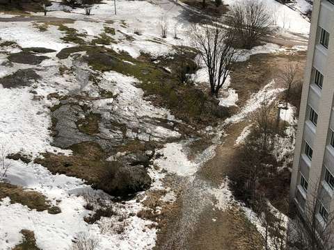 Kuvassa lumen sulamisvesiä kallioisella kerrostalon pihamaalla.