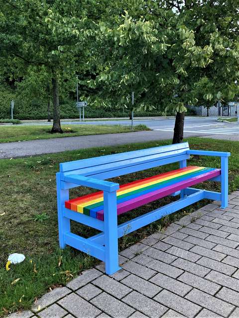 Sateenkaarivärein maalattu puistonpenkki.