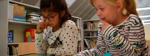 Kaksi oppilasta käyttävät tablettia.