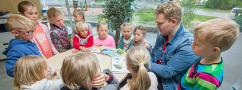 Pupils and their teacher around the table.