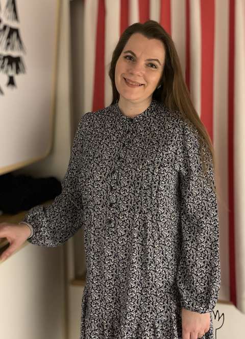 Tia seisoo ja katsoo hymyillen kameraan. 