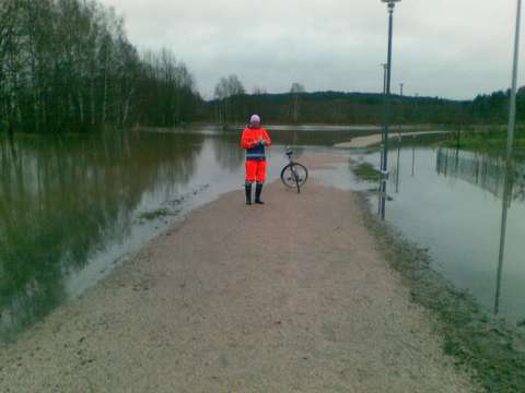 Kuvassa ympäristötarkastaja tulvivan puistotien keskellä.