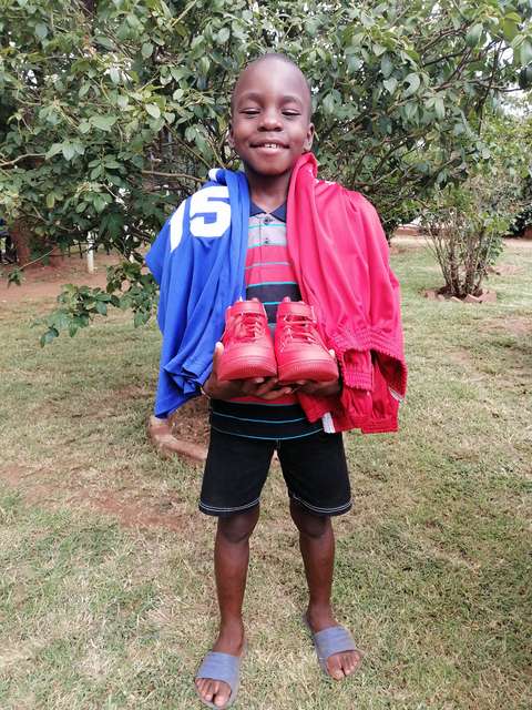 Lukion kummilapsi pitelee käsissään lahjaksi saamiaan jalkapallokenkiä.