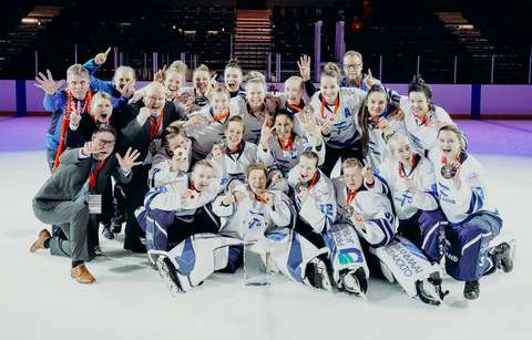 Naisten ringettejoukkue pelivarusteissaan ja MM-kultamitalit kaulassa ryhmäkuvassa jäähallin jäällä.