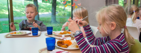 Kolme oppilasta syömässä.