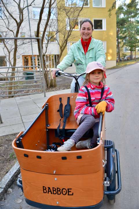 Äiti ajaa tavarapyörällä lapsi kyydissään.