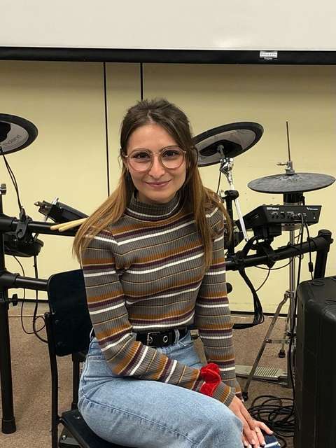 Nainen istuu rumpusetin edessä.