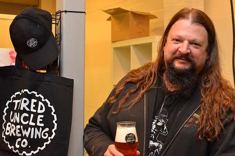 Luca Coelho kohottaa olutlasia Tired Uncle-panimon kaupan tiskin takana. 