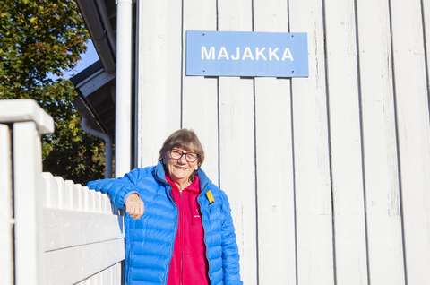 Nainen nojaa ulkona kaiteeseen ja katsoo kohti kameraa.