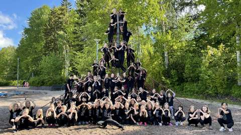 A large group of young people in front of and on a climbing frame. They all show heart shapes with their hands.