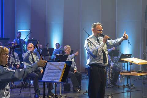 The conductor and players of the Police Symphonic Band give a tumbs-up.