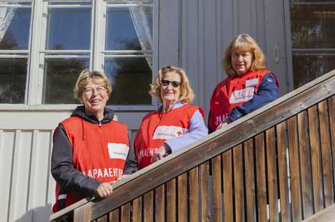 Katri Rannisto, Paula Mäntysalo ja Raija Lerkki nojaavat kaiteiseen Punaisen Ristin vapaaehtoisliivit päällään. 