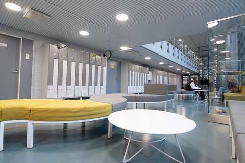 Aulautrymme med bänkar och bord, studerande syns i bakgrunden