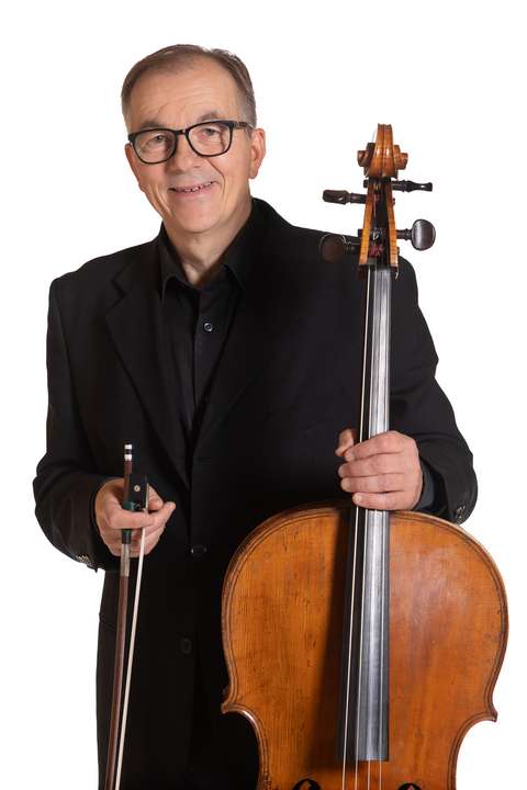 Cellisten håller i en cello och ler.