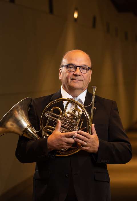 Valthornspelaren ler och håller i valthornet.