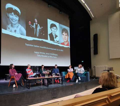 Panelistit istuvat vierekkäin keskustelemassa auditorion lavalla.