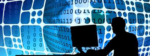 Henkilö istuu tietokoneen edessä. Taustalla tietokonekielen koodia.