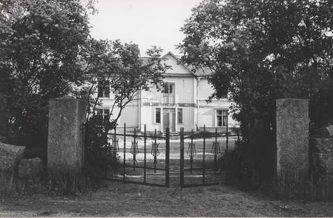 Rautaisen portin takana kartanorakennus.