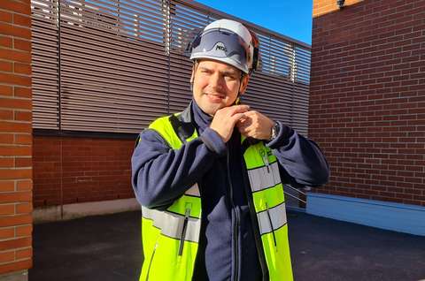 Tommy Alho pukee kypärää päähänsä. Hänellä on yllään keltainen huomioliivi.