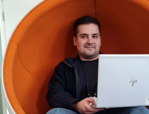 Tommy Alho istuu pallotuolissa kannettava tietokone sylissään.