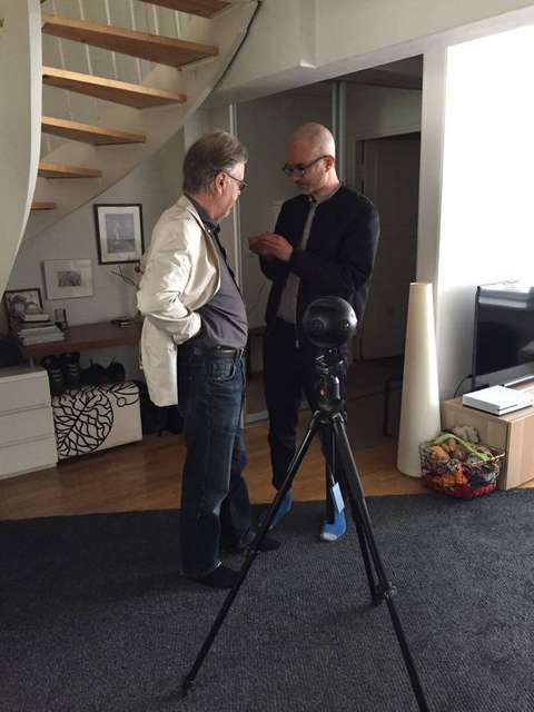 Kaksi miestä seisoo VR-kameran takana keskustelemassa. Taustalla kierreportaat.