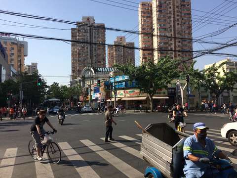 Kuva Shanghaista risteyksestä, jossa on joitain ihmisiä. Taustalla korkeita taloja.