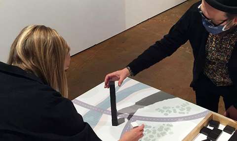 Kaksi henkilöä tutkailee esineitä pöydällä.