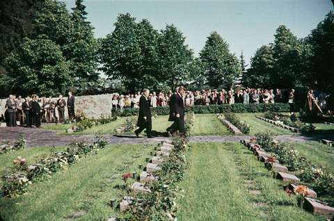 Ihmisiä kävelemässä hautajaissaattueessa hautausmaan poikki.