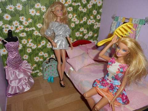 Nukkekodin interiöörikuva jossa Barbie-nukke kampaa itseään hiusharjalla ja toinen katsoo vieressä.