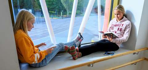 Oppilaat istuvat ikkunasyvennyksessä.