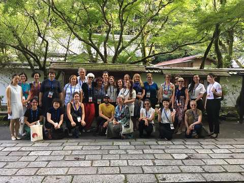 Ihmisiä poseeraa kameralle, taustalla talo ja puita.