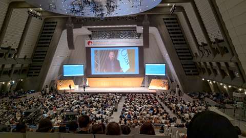 Kuva konferenssisalista jossa ihmisiä katsomassa esitystä joka on heijastettu kankaalle.