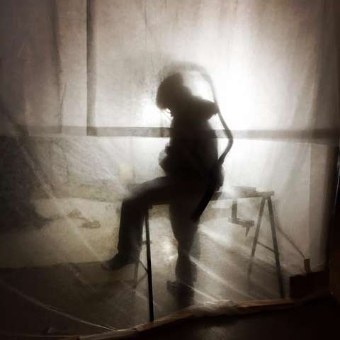 Konservaattorin hengityssuojainvarustetun suojapuvun siluetti puhdistusteltassa.