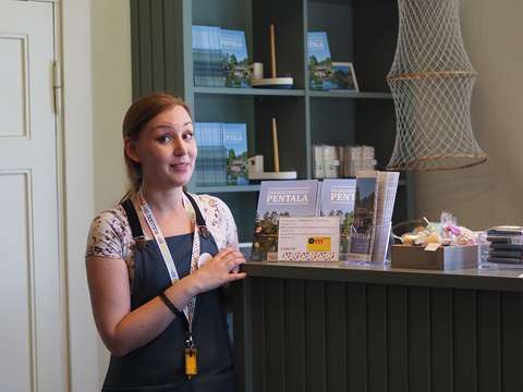 Museo-opas tyttö museokaupan tiskin takana yllättynyt ilme kasvoillaan.