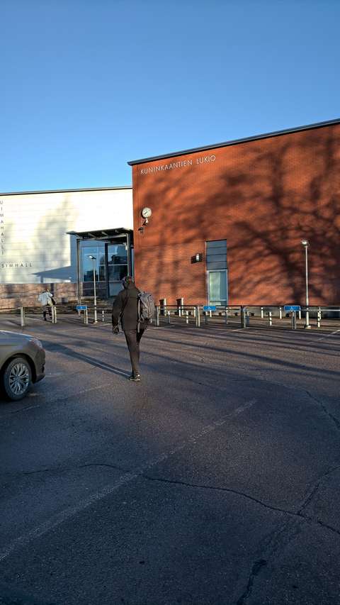 Nuori kävelee koulua kohti parkkipaikalta.
