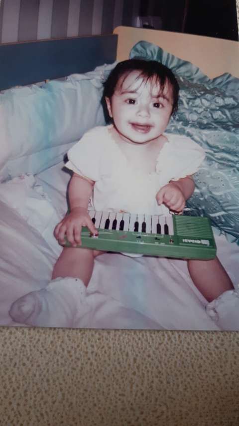 Pieni tyttö istuu sängyllä leikkiurut sylissä.