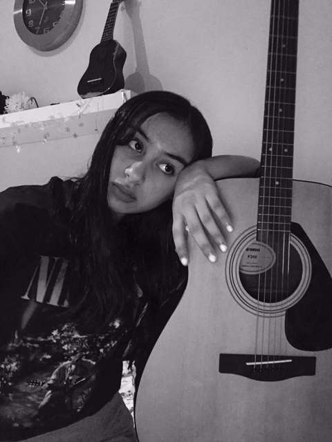 Nuori näinen nojaa kitaraan.